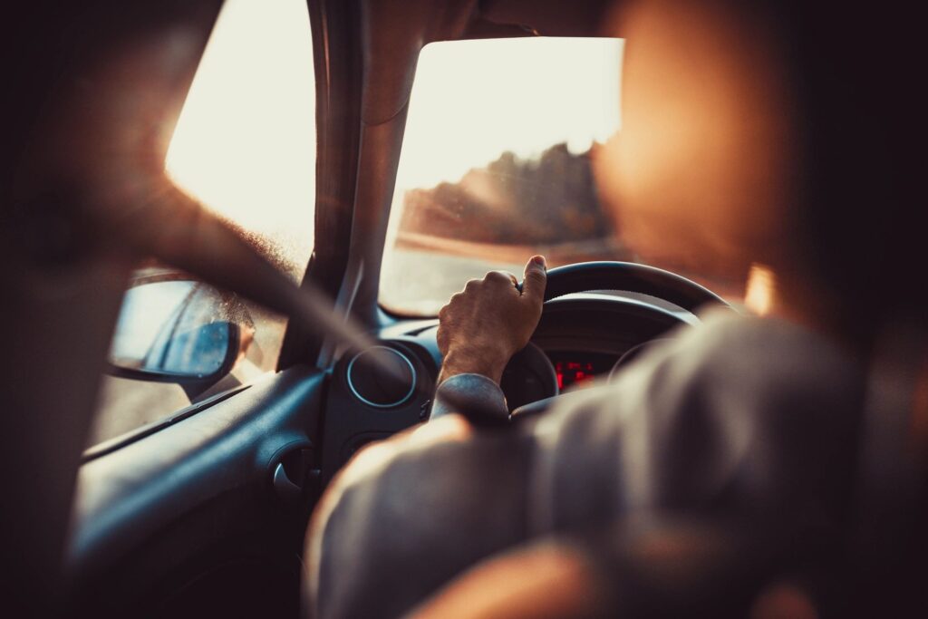 A person sitting in the driver 's seat of a car.