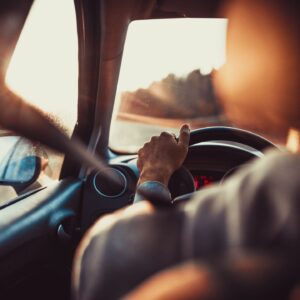 A person sitting in the driver 's seat of a car.