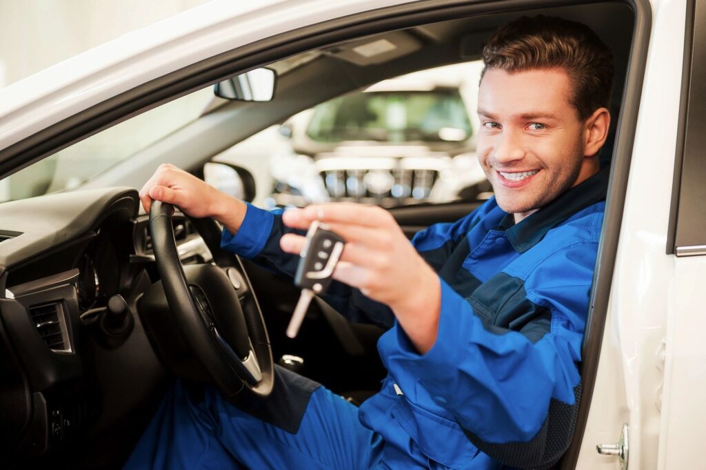 A man sitting in the drivers seat of his car holding a remote.