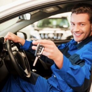 A man sitting in the drivers seat of his car holding a remote.