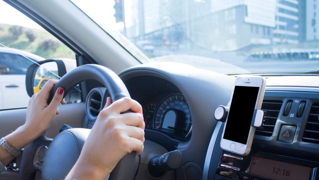 A person driving in the car with their phone on.